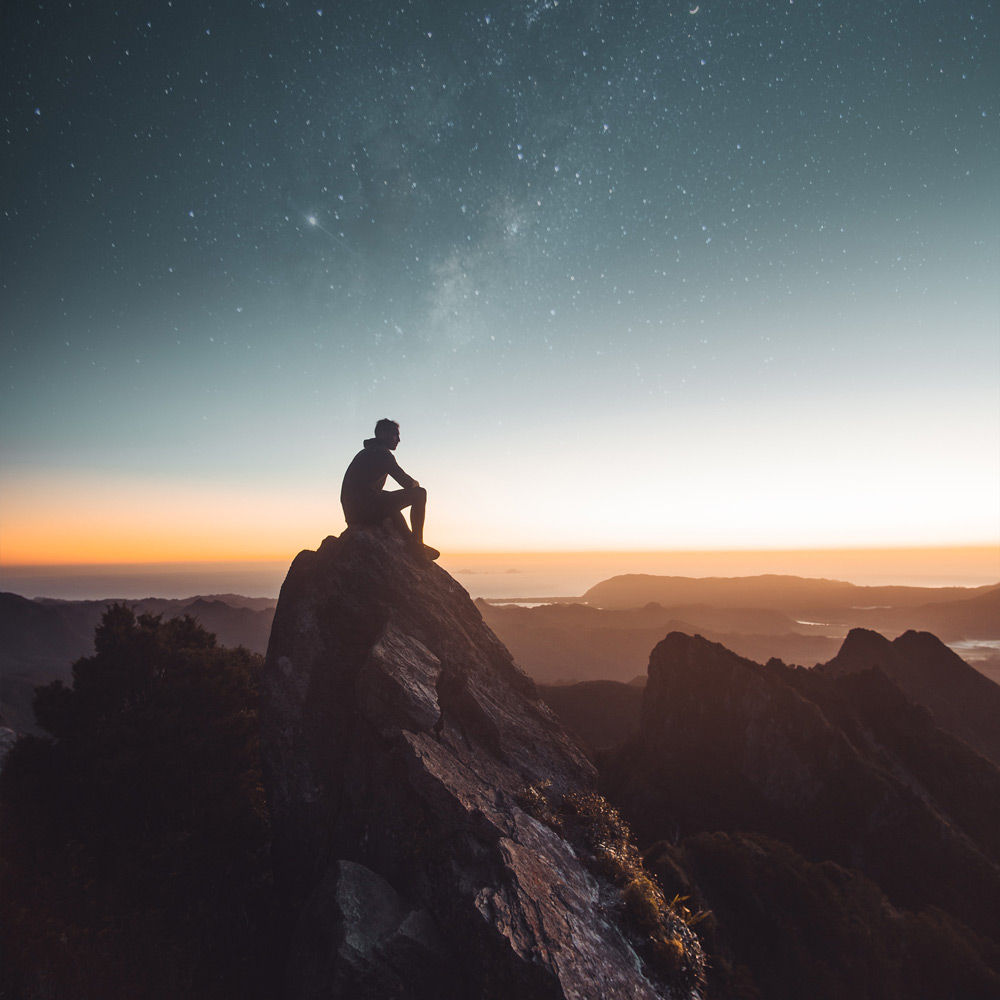 Dude sitting on a rock watching the sunset